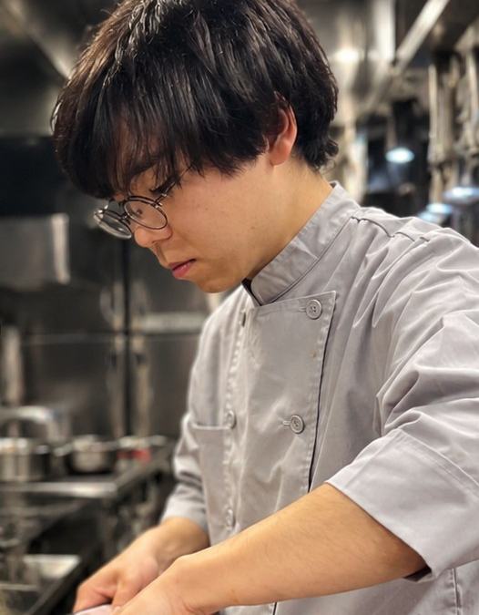厨房でパスタを仕上げる料理人